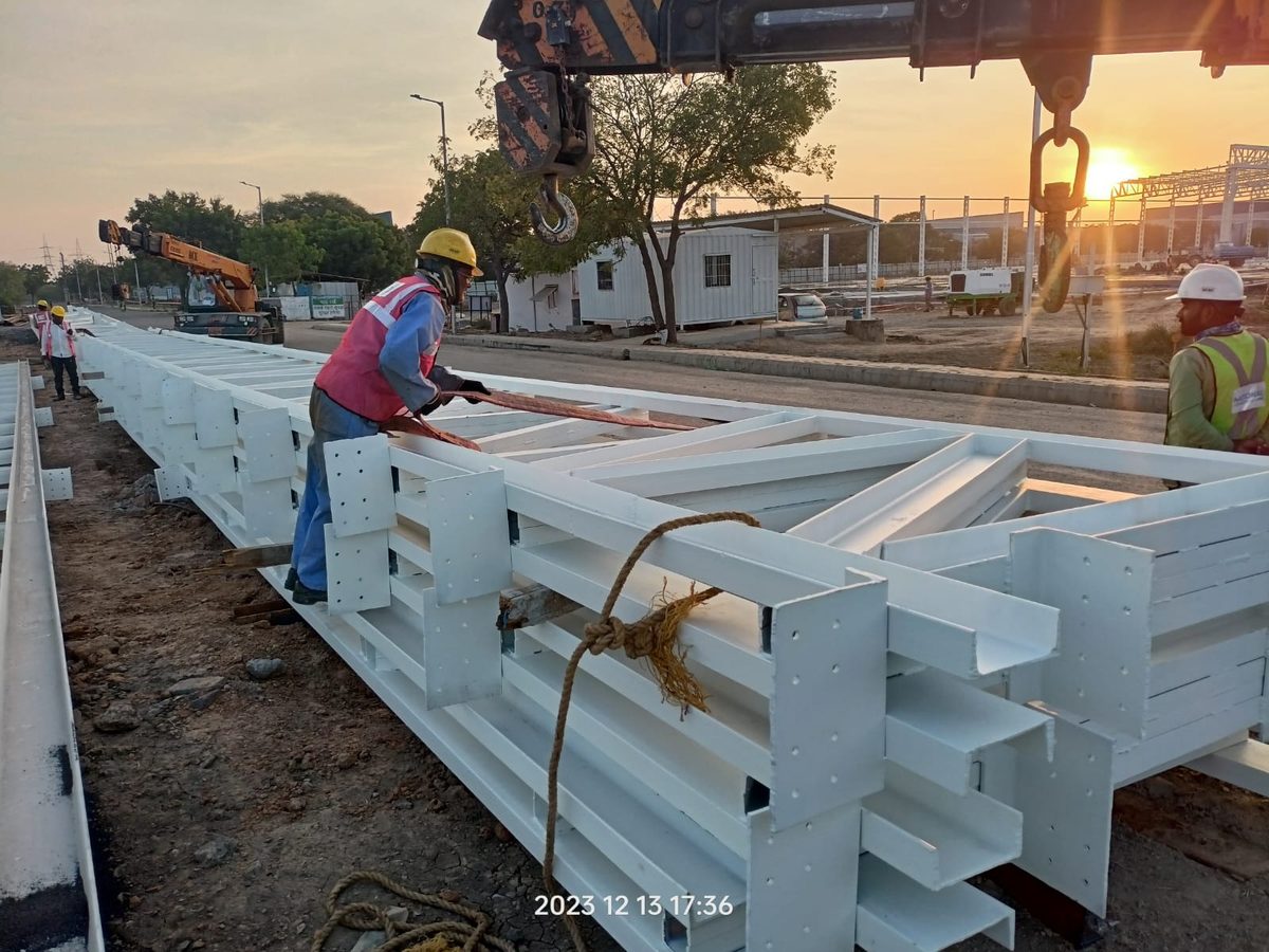 Coated structural steel members being rigged during erection at Sanand