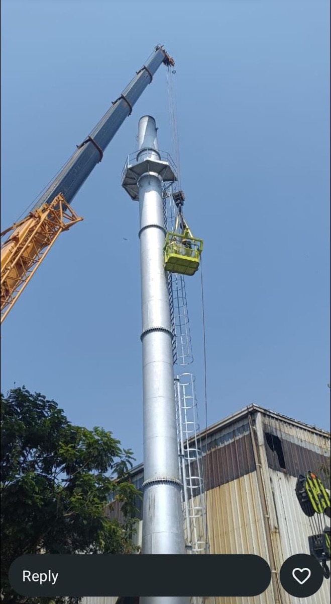 Workers in a crane cage aligning the top section of the chimney against the sky